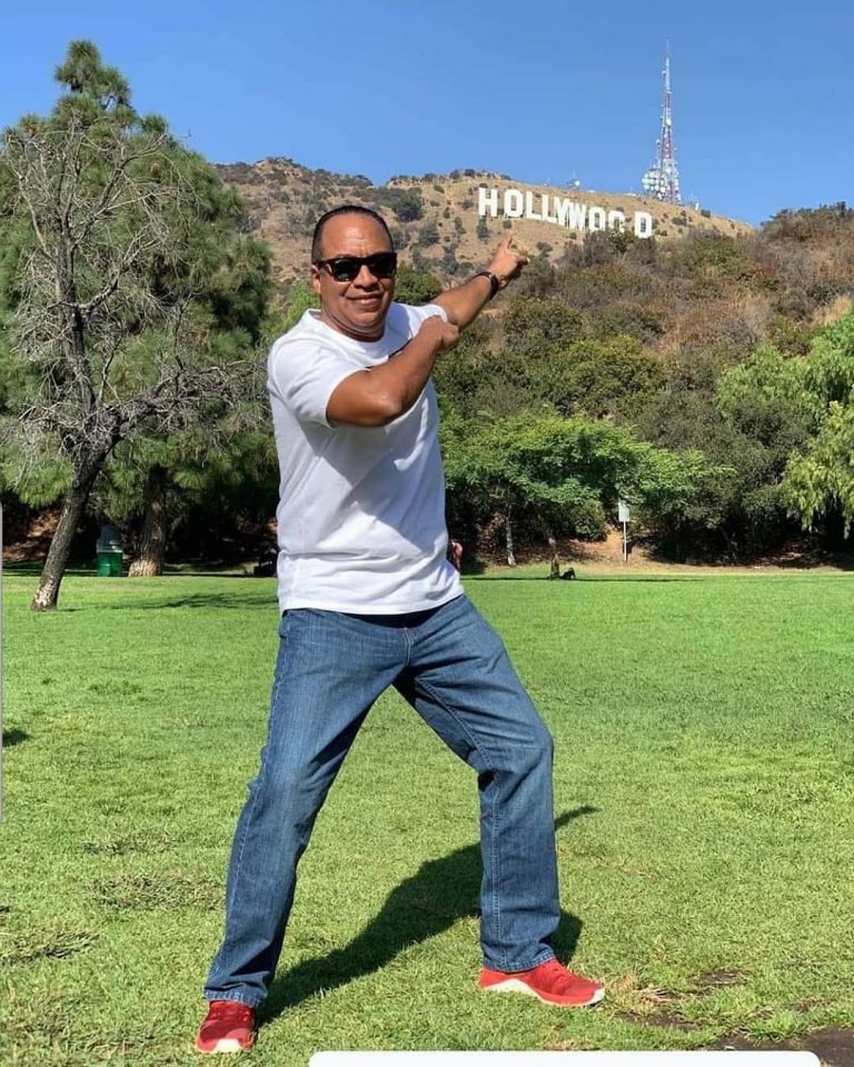 homem tirando foto com letreiro de Holywood ao fundo